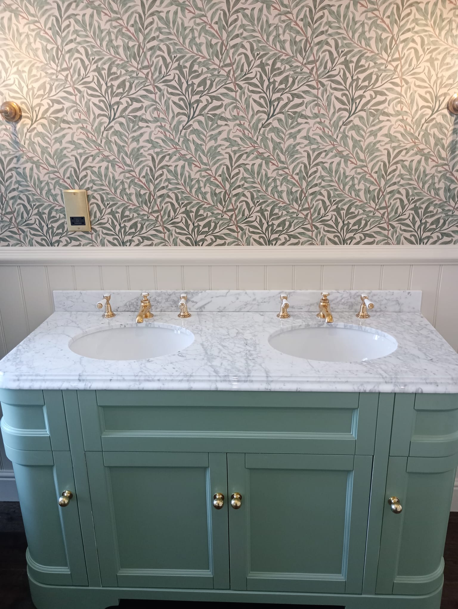 Double vanity with sage-green cabinetry and Willow Bough wallpaper