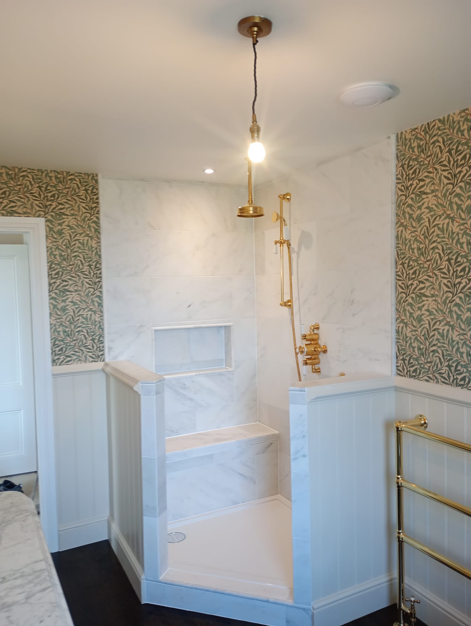 Walk-in marble shower with gold fittings