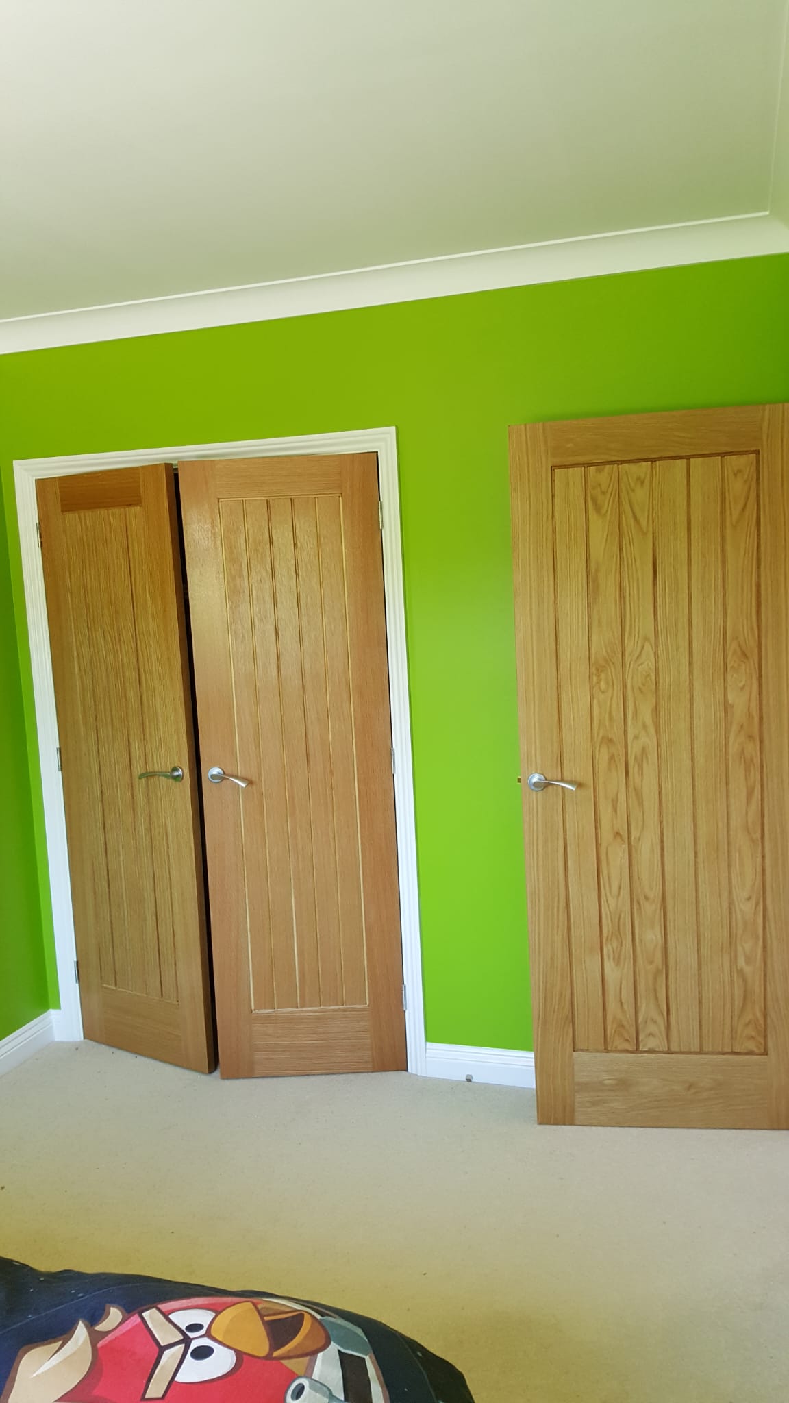 Bright green bedroom with an oak wardrobe