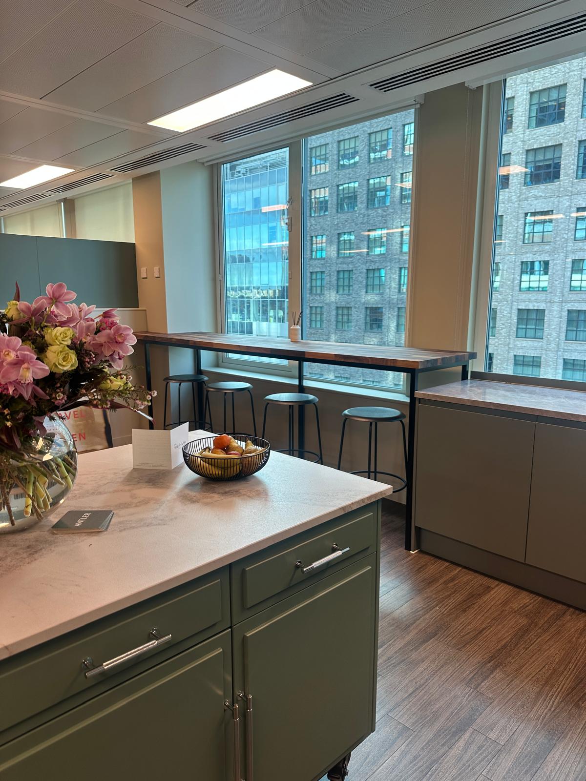 Office breakout kitchen with sage-green cabinetry and a marble worktop