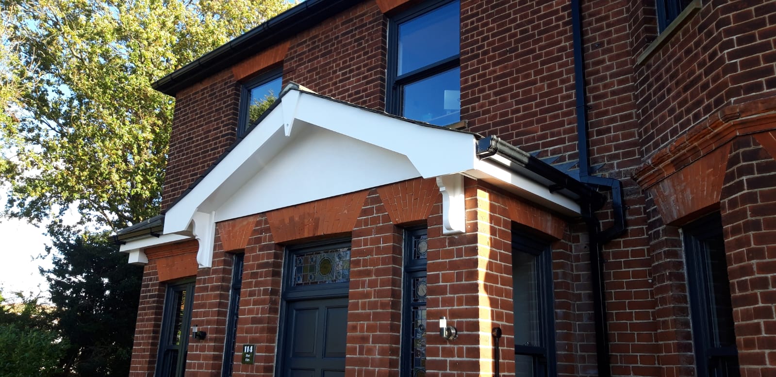 Completed gable porch canopy repainted in white against the restored brickwork